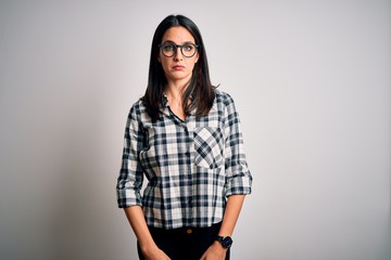 Young brunette woman with blue eyes wearing casual shirt and glasses over white background depressed and worry for distress, crying angry and afraid. Sad expression.