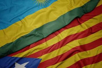 waving colorful flag of catalonia and national flag of rwanda.