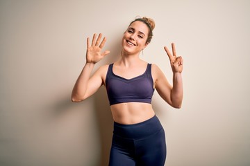 Young beautiful blonde sportswoman doing sport wearing sportswear over white background showing and pointing up with fingers number seven while smiling confident and happy.