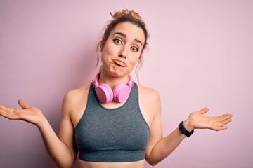Young beautiful blonde sportswoman wearing sportswear listening to music using headphones clueless...