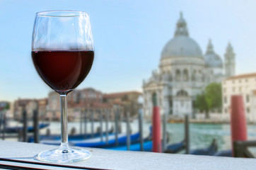 Glass of wine with view on gondolas and church in Venice, Italy