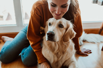 .pretty young woman caring and petting her adorable golden retriver dog. Accompanied at home during the quarantine caused by the covid19. Lifestyle © lubero