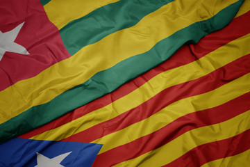 waving colorful flag of catalonia and national flag of togo.