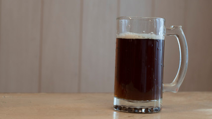 Glass mug of dark beer on the table with copy space