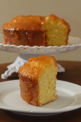 Slice of homemade orange cake with orange icing. White background.