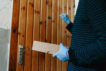 Grocery store shopping delivery man giving paper bag wearing blue glove as protection for covid 19 Coronavirus precautions.