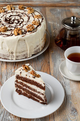 A slice of sponge honey cake with walnut and buttercream on old vintage table