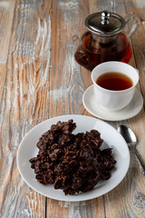 No-bake corn flakes cookies with dry fruits, nuts and raisins with a cup of black tea on old wooden table