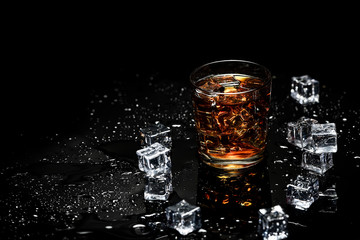 Whiskey with ice cubes on black background from above.Glass of scotch and ice cubes on a on black background