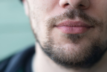 beard of a man close-up, on a turquoise background. Concept - unshaven beards, barbershops closed.