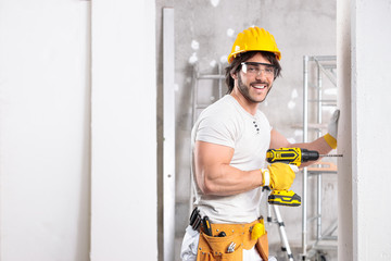 Smiling friendly builder working with a drill