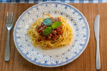 
spaghetti pasta with bolognese sauce and basil on the plate. Top View.