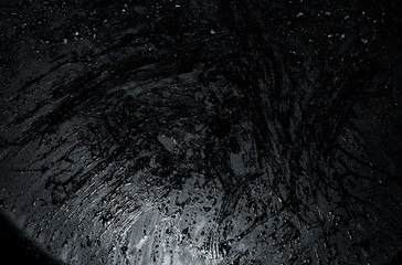 Fototapeta premium Finished dinner plate. Post-meal oil patterns and glitters on a matte black dinner plate. Glittery dark black background.