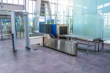 X-ray machine for screening passenger luggage with frame metal detector at the airport check-in counter.