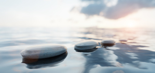 Fototapeta na wymiar Zen stones on calm water at sunset. Spa wellness and harmony.