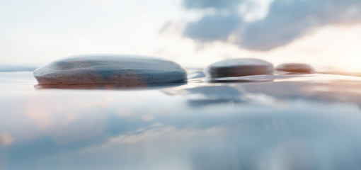 Zen stones on calm water at sunset. Spa wellness and harmony.