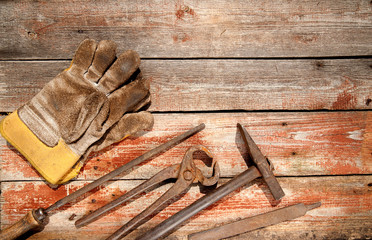 Obraz na płótnie Canvas working hand tools hammer, file, gas wrench, dirty gloves lie on a wooden background