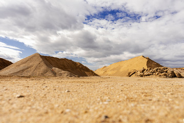 Open pit gravel mining. Large piles of construction sand and gravel used for asphalt production and building. Limestone quarry, mining rocks and stones. Sunny day