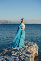 Fototapeta na wymiar Young woman on the sea in blue dress