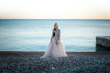 Fototapeta na wymiar Yong girl on the beach and rock in long dress
