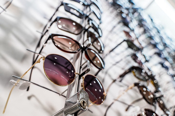 Raw of fashion elegance sunglasses in the store. Showcase with sunglasses in modern ophthalmic store. Closeup.