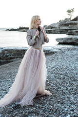 Yong girl on the beach and rock in long dress