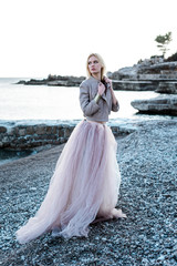 Yong girl on the beach and rock in long dress