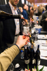 Closeup of a man pouring red wine into a wine glass.