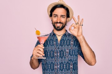 Young handsome hispanic bohemian hipster man with bear drinking a summer cocktail doing ok sign with fingers, excellent symbol