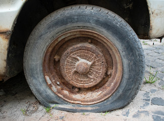 Old flat tire on a retro car. Urban motif