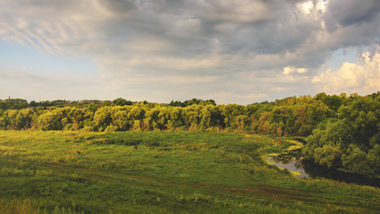 Fototapeta na wymiar Summer landscape with green field and cloudy sky