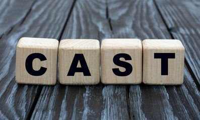 concept word CAST on cubes on a dark wooden background