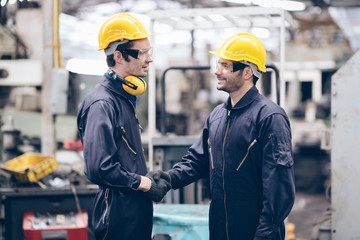 technician and partnership shake hand at machine in factory