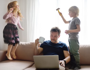 Tired father with his two kids during quarantine. Stay at home concept. Online working and...