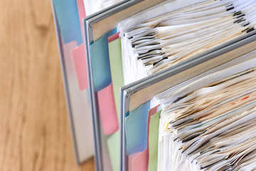 Closeup of binders with papers and tabs. Stack of business papers, bills or documents in standing...