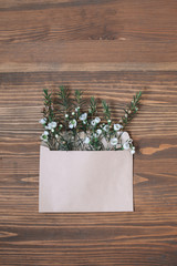 Opened craft paper envelope full of spring blossom are lying on the brown wooden background