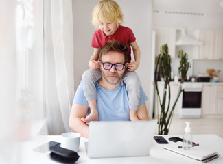 Man working from home with laptop during quarantine. Home office and parenthood at same time....