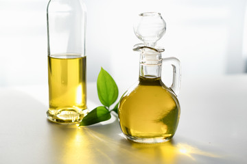 against the window, olive oil in a decanter and in a glass bottle, with a green leaf