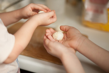 Children making a cottage cheese balls Russian syrniki in the home kitchen.