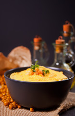 Traditional appetizer hummus with chickpea in a black bowl.