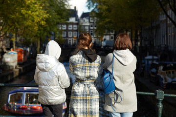 Tourists standing on a bridge looking at an Amsterdam canal