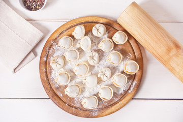 Homemade uncooked russian pelmeni meat dumplings italian ravioli on cutting board.