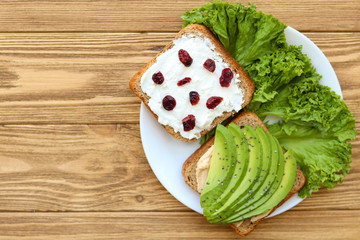 Healthy breakfast, whole grain bread with avocado, feta cheese and dried cranberries
