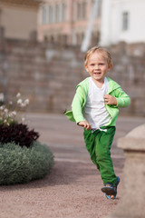 Fototapeta premium A blond child of European appearance in green clothes happy runs along the Senate Square in Helsinki in Finland.