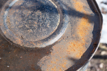 inverted rusty barrel made of metal for water, in the spring against the backdrop of snow.