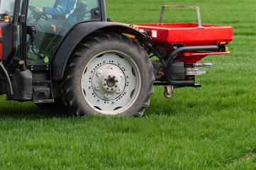Fototapeta na wymiar Tractor spreading artificial fertilizers