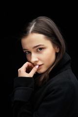 Dramatic portrait of a beautiful lonely girl  isolated on a dark background. Young brunette woman with healthy clean skin. People, emotions, stress and health care concept.