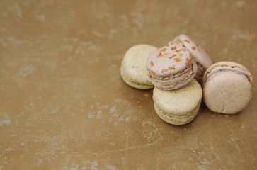 Yellow homemade macarons with blossom are lying on the golden background.