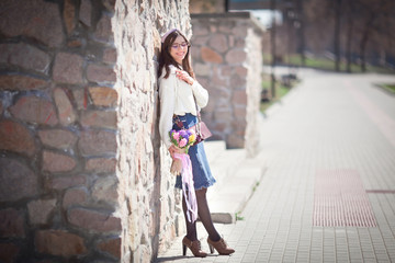 beautiful girl walks with a bouquet of spring flowers along the promenade