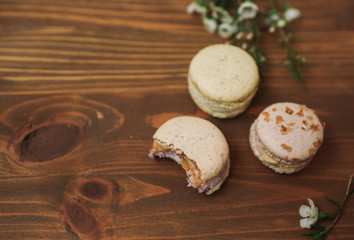 Obraz na płótnie Canvas Three homemade macarons with blossom are lying on the wooden background.
